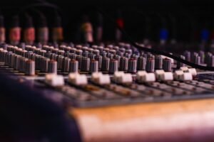 Close-up of a professional audio mixing console with knobs and sliders, essential for music production.